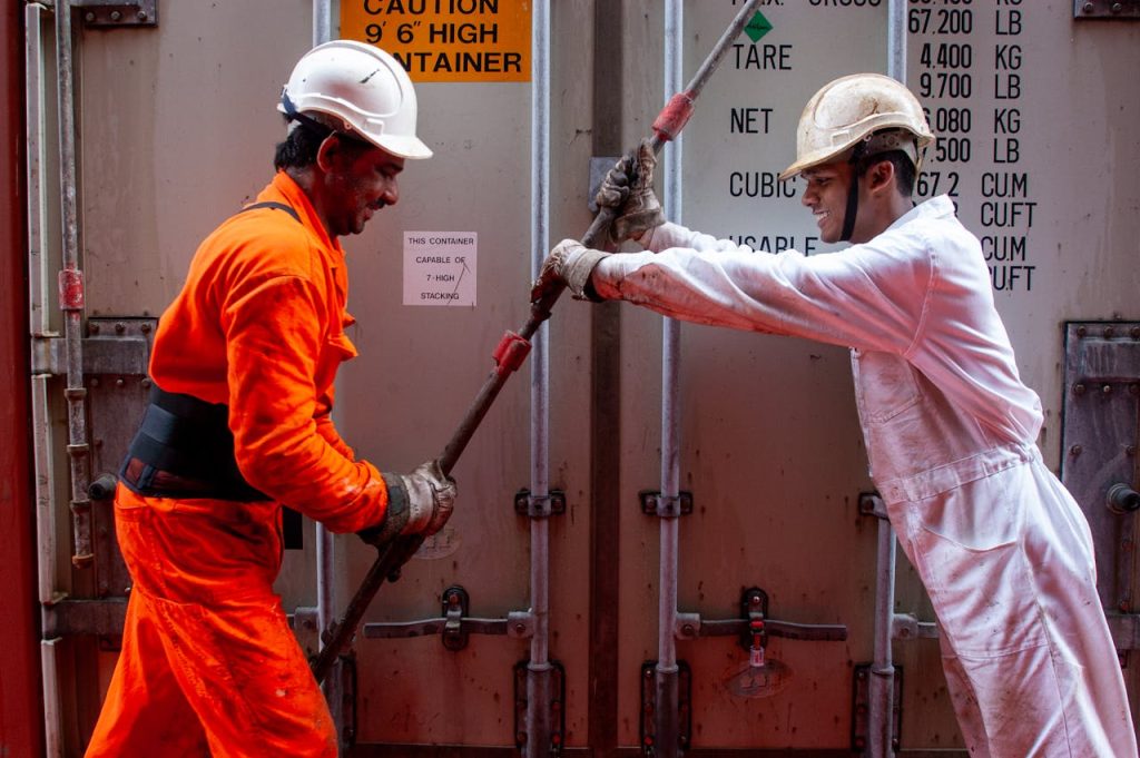Two dockworkers securing a container on a ship, emphasizing teamwork and safety.